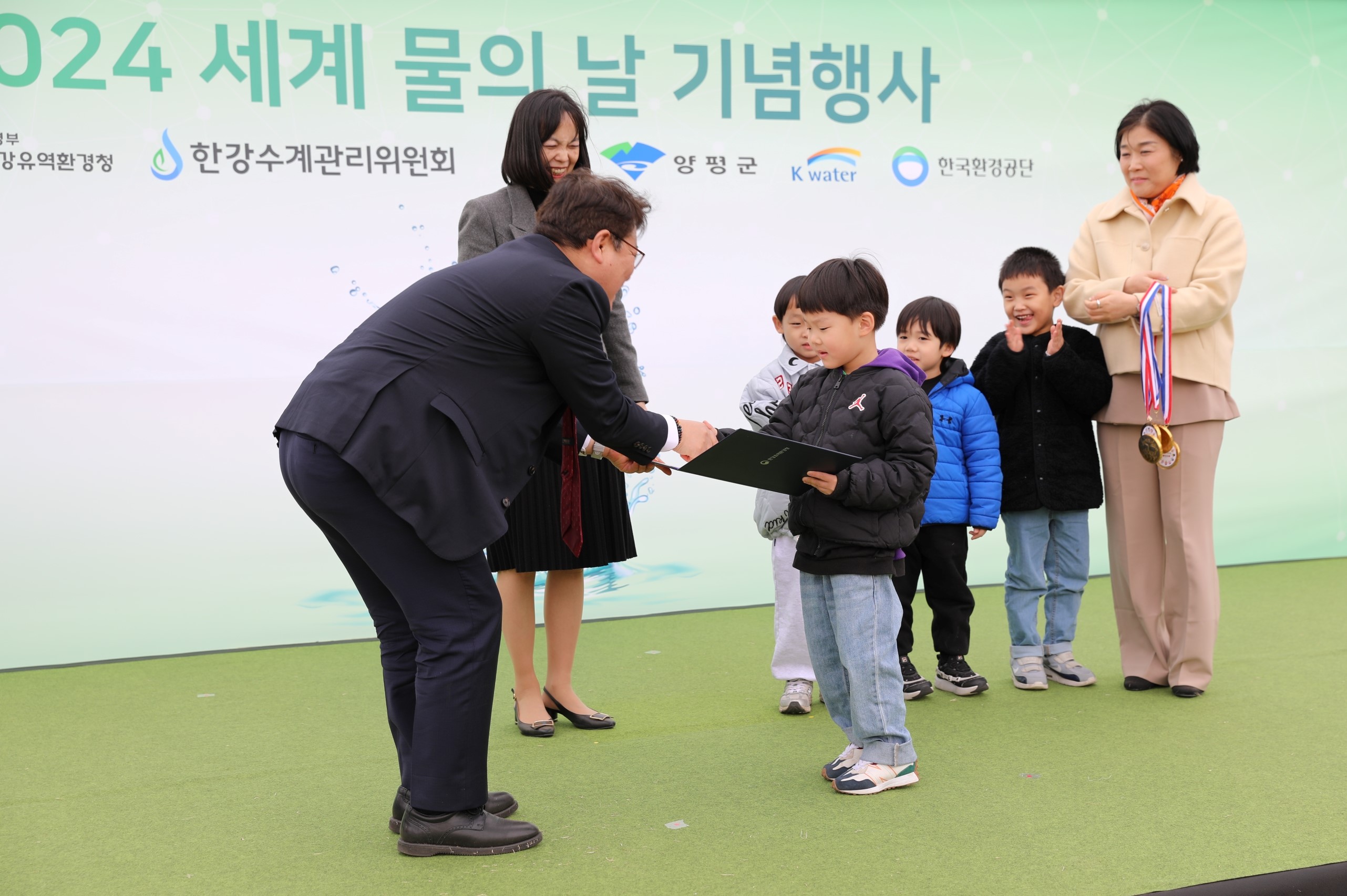 사진2. 김동구 한강유역환경청장(왼쪽)이 22일, 경기도 양평군 수풀로 양수리에서 어린이 그림공모전 수상팀에게 상장을 수여하였다.